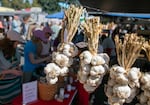 Garlics hangs in braids from the top of the Loughridge Farms tent in North Plains, Ore., on Aug. 12, 2023. Garlic can be split into two categories, hard and soft tops. Soft-top garlic can be tied and knotted into braids and is the most common garlic seen in grocery stores.