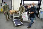 In this Dec. 15, 2020, file photo, Staff Sgt. Noel Bueno, left, Pfc. Saurav Shrestha, center, and Mark Robinson, right, take delivery of a box of the first shipment of the Pfizer vaccine for COVID-19 before putting it in a freezer shortly after it arrived at Madigan Army Medical Center at Joint Base Lewis-McChord in Washington state, south of Seattle.