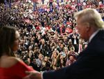 Arkansas Gov. Sarah Huckabee Sanders and former President Donald Trump talk as attendees cheer during the second day of the Republican National Convention in Milwaukee on Tuesday.