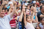 Viewers raise their hands to cheer performers on stage at the Jade International Night Market held at Portland Community College campus in Southeast Portland, Ore., on Aug. 19, 2023.