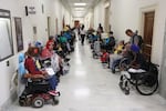 Members of the disability rights group ADAPT line a hallway on either side. Many people are in wheelchairs; some are carrying signs.