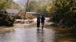 People walk through a flooded street following Hurricane Helene.
