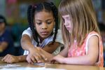 Lyric Carvalho, left, and Eleanor Christensen work together during a reading lesson in Coral Walker’s first grade class.