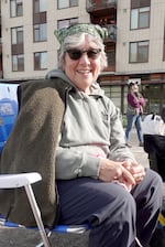 Beth Kent, 75, sitting across the street from the U.S. Immigration and Customs Enforcement facility in South Portland, Oct. 23, 2025. Kent, a retired nurse, said she has more time to protest now than she did when she was a student in the 1960s-1970s.