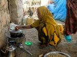 Fatouma Zahara Hasan heats water at the front of her home where she sells traditionally made Ethiopian coffee in the town of Chifera, in Ethiopia's Afar region.
