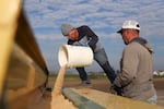 Jose Vasquez, left, and Eloy Luevanos fill up a grain hopper with winter barley seeds before planting at Goschie Farms in Mount Angel, Ore., Tuesday, Oct. 31, 2023.