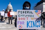 A protester with a sign saying "Federal Employees Don't Work for Kings" demonstrates in support of federal workers and against recent actions by President Trump and Elon Musk on Presidents Day in Washington, D.C.