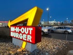 FILE - Customers pass by the illuminated sign outside an In-N-Out Burger restaurant Sunday, Dec.c 8, 2024, in Lone Tree, Colo. An employee was among three people killed in a shooting at an In-N-Out Burger restaurant in southern Idaho on Aug. 1, 2026.