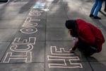 Indivisible organizer Tara Velarde writes, “ICE out of PDX health care!” during a demonstration at Dawson Park, across the street from Legacy Emanuel Medical Center, in protest of the hospital working with ICE to treat detainees they harm during arrests in Portland, Ore., on Jan. 10, 2026.