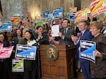 FILE - Washington Gov. Bob Ferguson holds up the state's first income tax, also known as the "millionaires tax," after signing it into law on March 30, 2026, in Olympia.