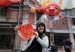 A woman holds a spring couplet with dragon patterns that she drew herself for the upcoming Lunar New Year celebrations at the Dihua street market in Taipei, Taiwan, Thursday, Feb. 8, 2024. Taiwanese shoppers started hunting for delicacies, dried goods and other bargains at the market ahead of the Lunar New Year celebrations which fall on Feb. 10 this year.