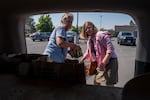 Friends Tari Donohue, left, and Karen McCarthy load food, drinks, clothing and supplies for evacuees from the Bench Fire. They spent a total of $270.86 on supplies with money donated from community members.