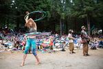 Attendees watch the main stage performances and a woman spinning five hula-hoops from the hill. There are four different stages, including the main stage at the Northwest String Summit.