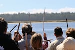 Over a hundred gathered at Bullards Beach in Bandon, Oregon on June 28, 2024 for the 35th Annual First Salmon Ceremony during the Coquille Indian Tribe’s Restoration Celebration. As the bones of the ceremonial salmon were returned to the Coquille River, people sang in prayer and raised driftwood sticks to the sky.
