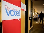 A sign saying “Register & vote!” is on display at the King County elections office in Renton, Wash., in 2020.
