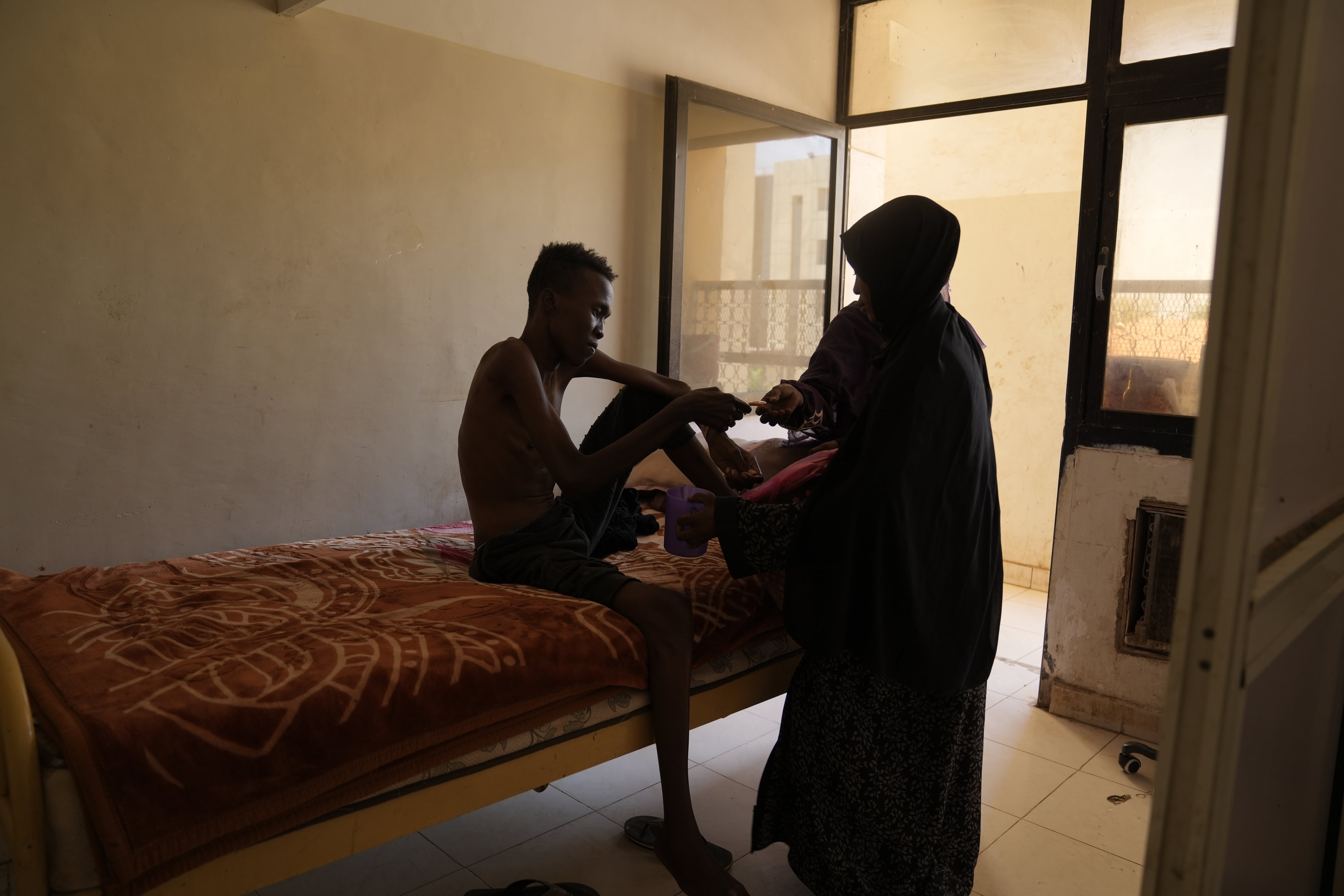 Wala'adin Abdurahaman, 22, photographed at a military hospital in Khartoum. The rebel RSF forces detained him for more than 18 months at Soba Prison in Khartoum. He said he was tortured constantly and given irregular and tiny quantities of food and water. Freed by the Sudanese army when they recaptured Khartoum, he had lost so much weight that when he reached his home, his mother initially refused to open the door as she didn't recognize her son.
