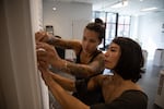 Bear Patton (left) and Taemi Izumi hang name placards for the Be Nice (White) You're In Bend exhibit at Scalehouse in Bend, Ore., on Aug. 6, 2021.