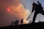 Firefighters work as a brush fire burns in Pacific Palisades, California.