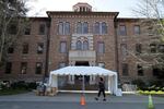 In this March 19, 2020, file photo, an employee walks near an entrance to Western State Hospital in Lakewood, Wash. As coronavirus cases top 200 in Washington state's largest psychiatric hospital, officials are implementing new procedures to try to get it under control. Making matters worse, the economic downturn that resulted from the pandemic, and the loss of revenues needed to run state government, is forcing the Department of Health and Human Services to make budget cuts, including layoffs at Western State Hospital.