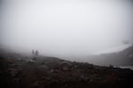 From left, Neal Ludevig, Marcela Fernandez and Aaron Hartz hike next to snowfields on South Sister in Central Oregon, Sunday, Oct. 18, 2020. The Oregon Glaciers Institute organized a funeral for the Clark Glacier after declaring it dead earlier in the summer.