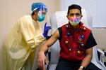 Dr. Dakotah Lane, a member of the Lummi Nation, right, receives a COVID-19 vaccination from registered nurse Alyssa Lane, his cousin, Thursday, Dec. 17, 2020, at the Chinook Clinic on the Lummi Reservation, near Bellingham, Wash. The Native American tribe began rationing its first 300 doses of vaccine as it fights surging cases with a shelter-in-place order.