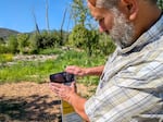 John Speece takes a picture of the creek using a photo station his team set up, August 4, 2025. Anyone can submit photos to help track natural changes over time.