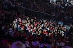 People sit in the rows of an arena as they attend a Turning Point USA event at the University of Mississippi on October 29, 2025. Many people are wearing red Make America Great Again baseball caps.