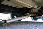 The exhaust pipe of an abandoned car missing its catalytic converter, rests on the ground in Philadelphia on Thursday, July 14, 2022. Officers normally assigned to a unit that deals with livability issues like graffiti, nuisance businesses and abandoned cars have been shifted to the city center and violent hot spots around Philadelphia, where the homicide rate reached a record high last year.