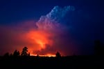 A nighttime scenery photo shows the sky glowing orange as the Bootleg Fire's light bounces off the smoke-filled cloudy sky.