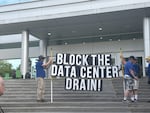 Opponents of data centers hold a sign outside the Hillsboro Civic Center ahead of a city council meeting Tuesday, June 2, 2026.