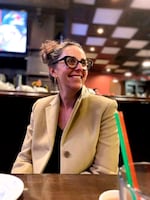 A person sitting at a bar or restaurant table smiles.