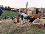 Kids slide down a grassy hill on scraps of cardboard while waiting for the Vaux’s Swifts to gather at sunset in Portland, Oregon.