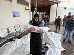 A woman carries a child killed in an Israeli airstrike in Rafah at the main Abu Youssef al-Najjar hospital's morgue on May 6, 2024. The hospital was later destroyed, following Israel's ground invasion of the city in pursuit of Hamas.