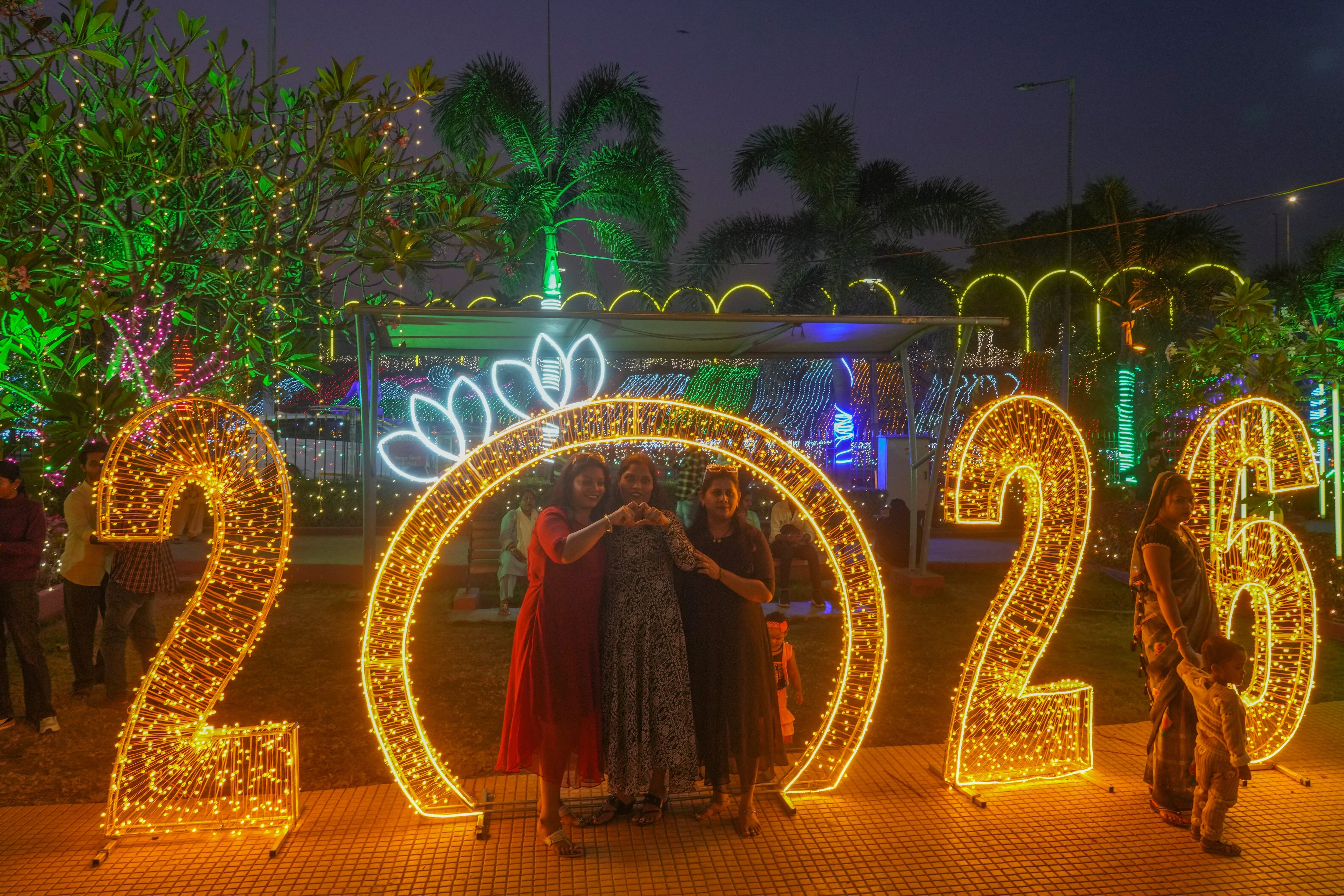 People pose for pictures near illuminated decorations on New Year's Eve in Mumbai, India, Wednesday, Dec. 31, 2025.