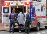 A man who was just revived from a near-fatal overdose climbs into the back of an ambulance, Dec. 13, 2023, in downtown Portland. 