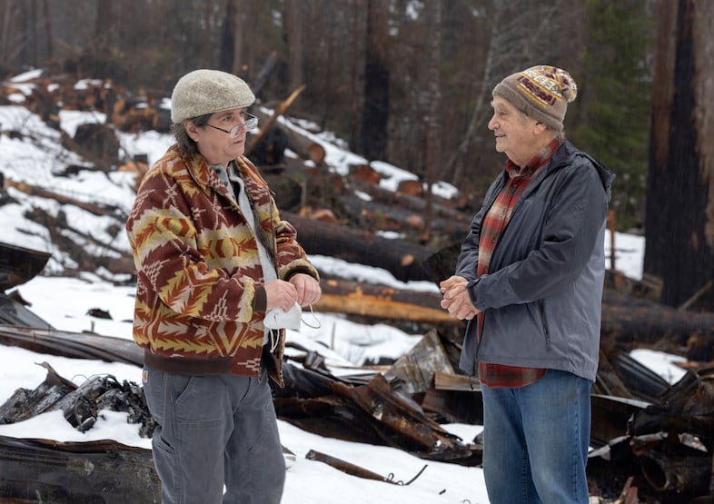 Woody Jackson, left, and Jay Hennigan, president of the Breitenbush Cabin Owners Association, survey the area where their cabin once stood in Breitenbush, March 5, 2021. The area and their cabin was destroyed by the Beachie Creek and Lionshead fires in 2020.
