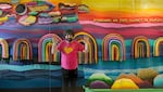 Artist Larry Peace-Love Yes, with his colorful mixed-media art installation located in the former Gap store at Lloyd Center, May 11, 2023. "Everyone on this planet is family,” says Peace-Love Yes, and that belief is represented in his 20-foot-long design. 