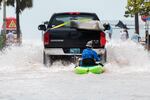 A truck pulls a man on a kayak on a low-lying road after flooding in the aftermath of Hurricane Ian, in Key West, Fla., Wednesday afternoon, Sept. 28, 2022.