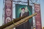 A domestically-built missile and banners showing portraits of the Iranian Supreme Leader Ayatollah Ali Khamenei, center, and armed forces commanders who were killed in an Israeli strike in June, are displayed in Baharestan Square, Tehran, Thursday, Sept. 25, 2025.