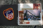 Photographs and a patch that belong to Rocco Fertoli are seen in a family album laid on a stone bench at the 9/11 Memorial in Lower Manhattan, New York, on August 10, 2026. One photo shows a uniformed Fertoli standing in front of a red fire truck. Another shows firefighters standing in front of a crane, with the destroyed World Trade Center in the background. The patch says: "FIRE DEPARTMENT CITY OF NEW YORK."