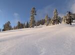 A ski slope with fresh snow on a blue sky day.