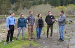 A man speaks to a group of people standing on a dry creekbed.