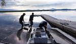 Mohammed Bawazeer (left) and Ian Riley carry a battery that will power the lake aeration system for 32 hours, even if the sun isn't shining.