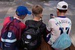 FILE - Three boys use their phones while sitting outside a school in Sydney, Monday, Dec. 8, 2025.