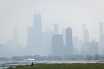 People sun tan in grass off the Lakefront Trail on the North Side as a haze of Canadian wildfire smoke blankets the Chicago area and creates poor air quality, Thursday, July 31, 2025.
