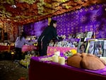 Peter Marín and his daughter Lucía put out candles lit for deceased loved ones at a community ofrenda at the Historic Oakwood Cemetery.