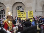 The procession accompanying Britain's King Charles III and Queen Camilla towards Buckingham Palace moves past anti-monarchist demonstrators on Saturday in London.