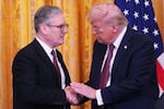 U.K. Prime Minister Keir Starmer, on the left side of the frame, and President Trump, on the right side of the frame, shake hands at a news conference at the White House on February 27, 2025. Behind them is a gold curtain and a U.S. flag.