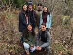 A group of students standing among winter plants.