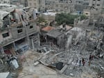 Palestinians walk about buildings destroyed in the Israeli bombardment in the Nusseirat refugee camp in the Gaza Strip on Sunday, Oct. 29, 2023.